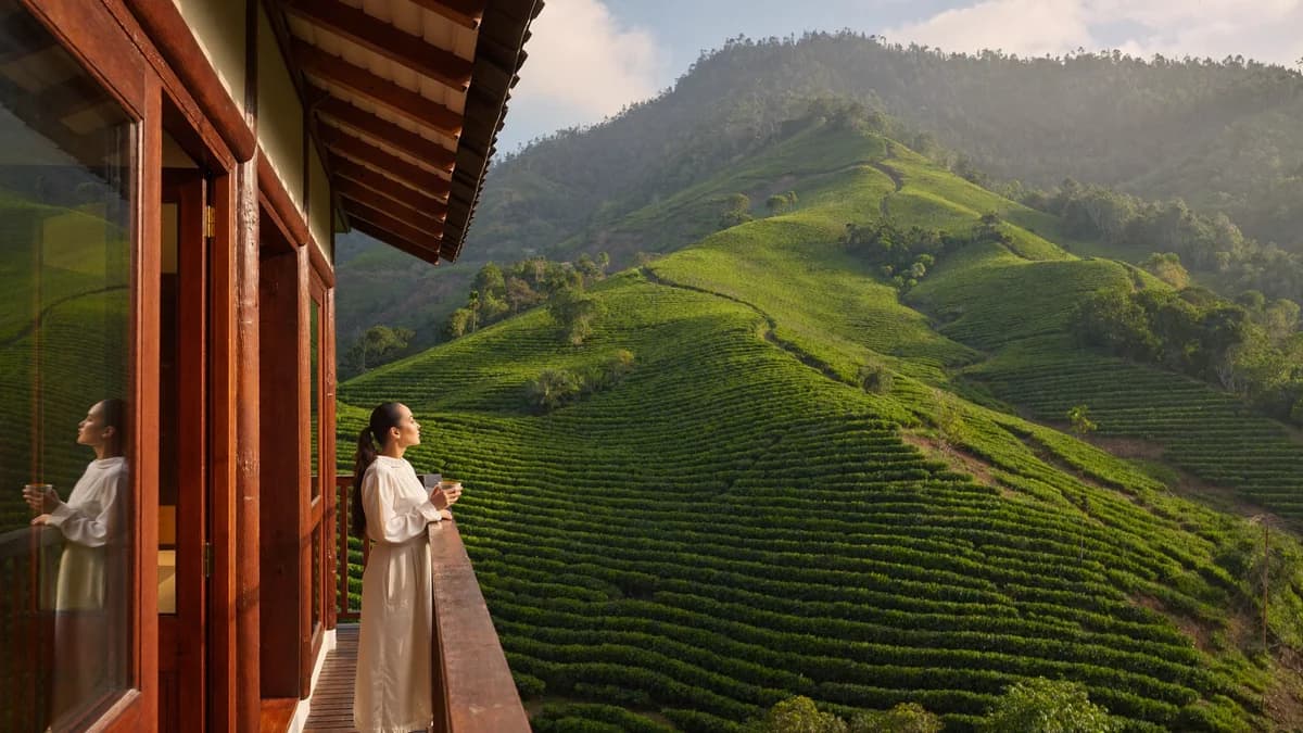 Travelers on a traditional colonial hacienda balcony overlooking rolling Andean coffee hills with a cup of origin coffee