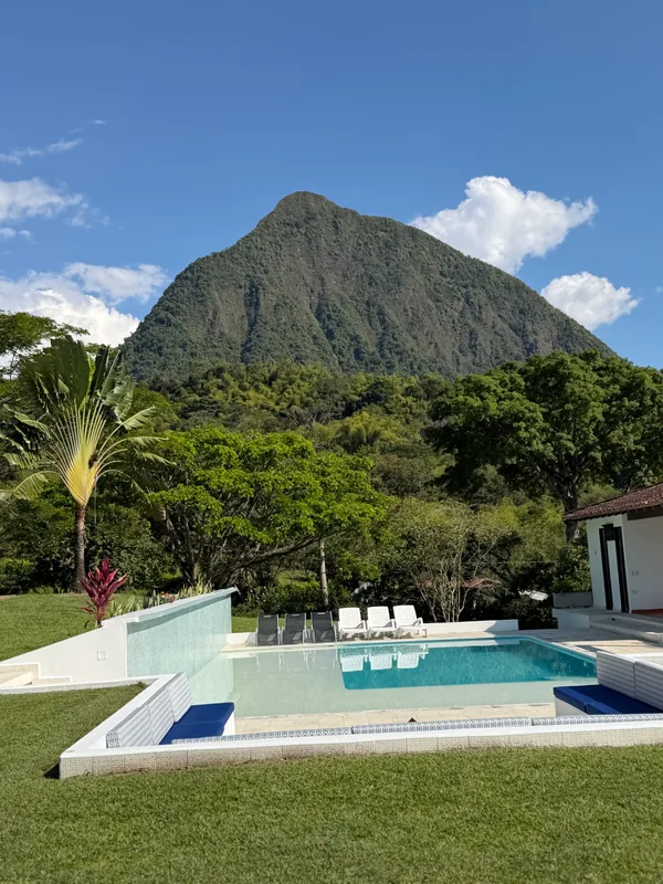 Outdoor wedding reception in the garden of a finca in Antioquia, long tables with flowers and lights in front of the mountains